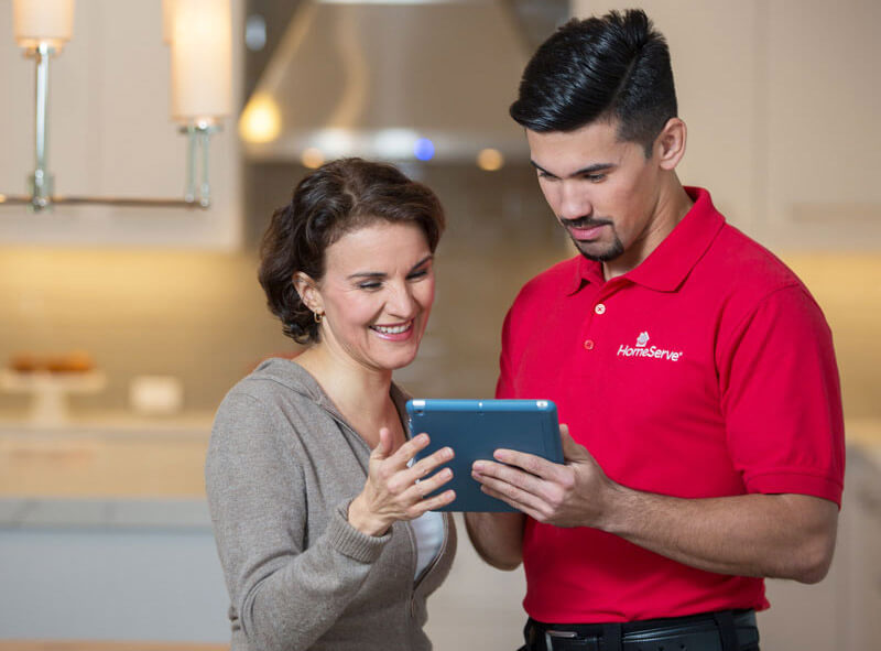 Woman looking at iPad with HomeServe repairman.